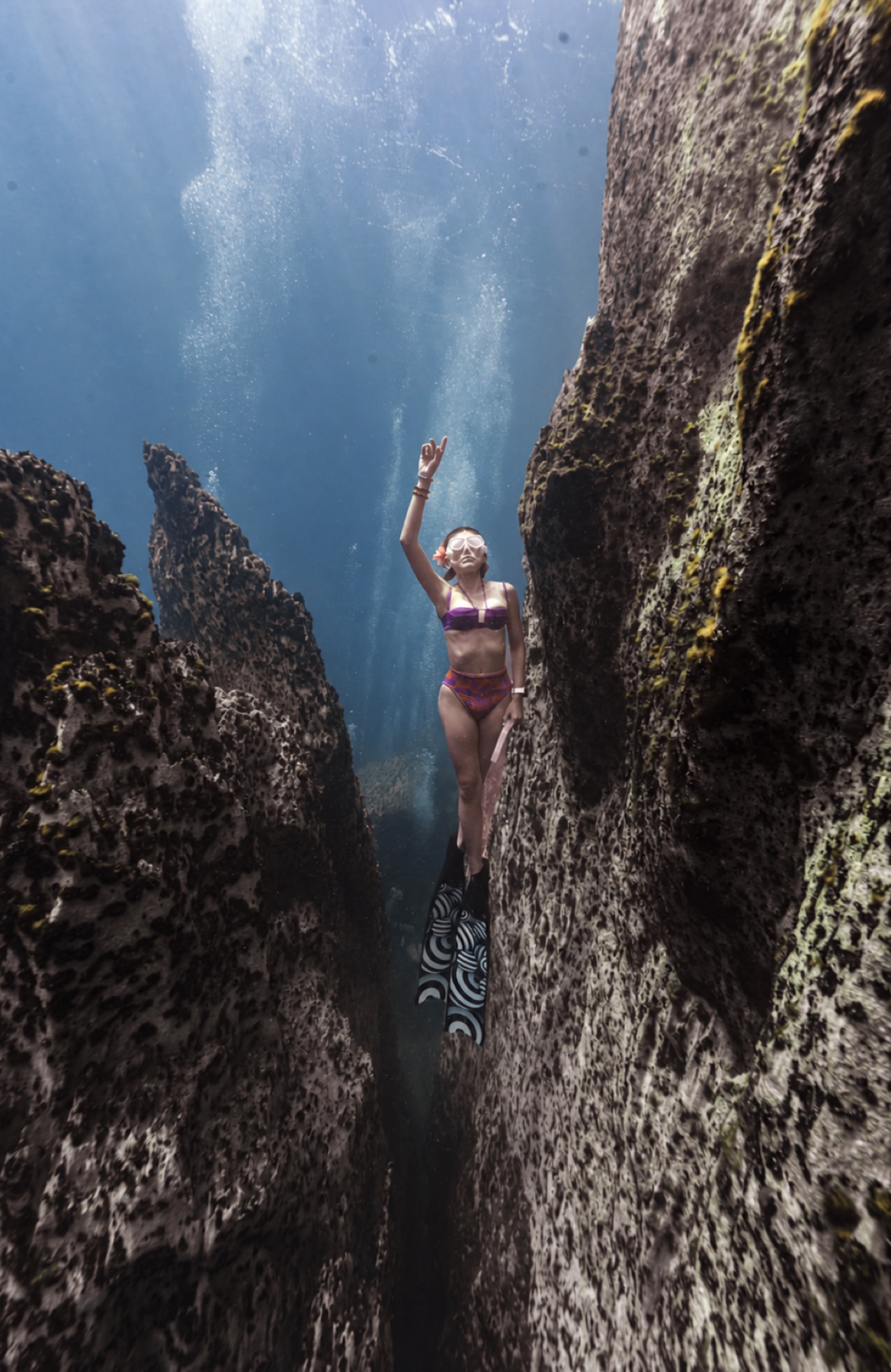 Freediver exploring a dramatic underwater rock canyon