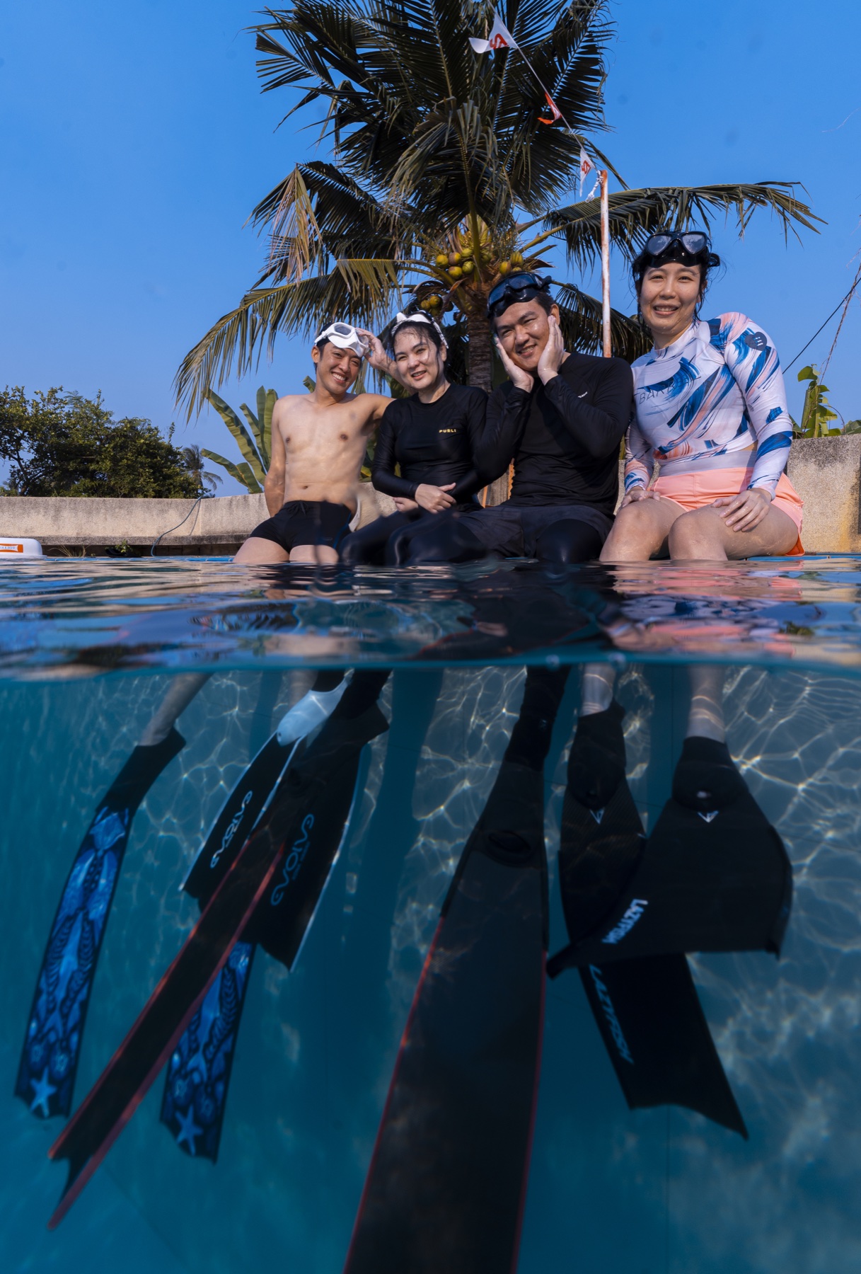 Freediving students sitting together at the pool edge above and below water